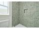 Beautiful tiled walk-in shower features a window, built-in niche, and modern fixtures at 323 Appian Ne Way, St Petersburg, FL 33704