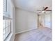 Neutral bedroom with a ceiling fan, soft carpet, and ample natural light from the large window at 3818 Cat Mint St, Tampa, FL 33619