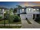 Townhome exterior featuring a two-car garage, lush landscaping, and a well-maintained lawn at 3818 Cat Mint St, Tampa, FL 33619