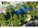 Aerial view of a tennis court surrounded by lush, tropical landscaping with palm trees at 17717 Gulf Blvd # 601, Redington Shores, FL 33708