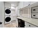 Organized laundry room with stacked washer and dryer, ample cabinet space, and a built-in desk at 1024 Sonata Ln, Apollo Beach, FL 33572