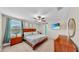 Spacious main bedroom featuring warm wood furniture, a ceiling fan, and natural light from the windows at 17102 Yellow Pine St, Wimauma, FL 33598