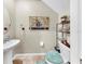Cozy powder room with decorative painting, pedestal sink, and neutral tile flooring at 17102 Yellow Pine St, Wimauma, FL 33598