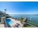 Aerial view of a waterfront property featuring a pool, private dock, outdoor seating, and lush landscaping at 26 Sunset Bay Drive, Belleair, FL 33756