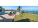 Backyard with a brick-paved patio, lounge chairs, manicured lawn, and waterfront access, perfect for relaxing at 26 Sunset Bay Drive, Belleair, FL 33756