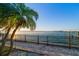 Backyard featuring palm trees and a waterfront with a wooden dock, ideal for enjoying the coastal scenery at 26 Sunset Bay Drive, Belleair, FL 33756
