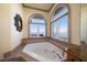 Spa-like bathroom with soaking tub under arched windows, offering serene waterfront views at 26 Sunset Bay Drive, Belleair, FL 33756