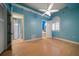 Bedroom featuring light blue walls, wood floors, ceiling fan and access to an ensuite bathroom at 26 Sunset Bay Drive, Belleair, FL 33756