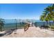 View of the private dock entrance with a paved walkway, lush palm trees, and secure gated access at 26 Sunset Bay Drive, Belleair, FL 33756