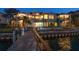 Beautiful exterior of waterfront home with balconies, dock, and lush landscaping at dusk at 26 Sunset Bay Drive, Belleair, FL 33756