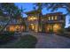 Elegant two-story house featuring lush landscaping, a fountain, and a brick driveway at 26 Sunset Bay Drive, Belleair, FL 33756