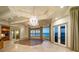 Stunning living room with water views, a chandelier, and access to a balcony at 26 Sunset Bay Drive, Belleair, FL 33756