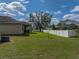 Spacious backyard with green lawn, white fence, and covered patio with grill at 4351 Highcroft Dr, Wesley Chapel, FL 33545