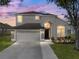 Charming two-story home featuring a well-manicured lawn, a two-car garage, and neutral stucco exterior at 4351 Highcroft Dr, Wesley Chapel, FL 33545