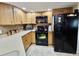 View of the Kitchen with wood cabinets and black appliances including a refrigerator at 7711 Innis Ct, St Petersburg, FL 33709