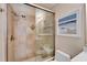 Shower with light tan tiles and a glass door, adjacent to a toilet at 17960 Gulf Blvd # 103, Redington Shores, FL 33708