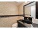 Elegant powder room with black fixtures, decorative wallpaper, and a stylish mirror at 17960 Gulf Blvd # 103, Redington Shores, FL 33708