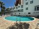 Community pool surrounded by lounge chairs and white buildings with balconies at 17960 Gulf Blvd # 103, Redington Shores, FL 33708