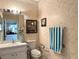 Bathroom with a vanity, commode with grab bars and patterned wallpaper at 2116 Nantucket Dr # 19, Sun City Center, FL 33573