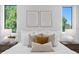 Bright bedroom with white bedding, decorative pillows, side tables, and large windows with lush green views at 2702 N Woodrow Ave # 2, Tampa, FL 33602