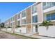 Modern townhome exterior features large windows, light wood accents, and a white privacy fence at 2702 N Woodrow Ave # 2, Tampa, FL 33602