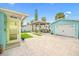 Well-designed backyard with paved patio, pergola with outdoor seating, manicured grass patches, and a garage at 421 77Th Ave, St Pete Beach, FL 33706
