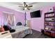 Bedroom with purple walls, dark wood floor, TV, and decorative shelves at 1203 Desmond St, Port Charlotte, FL 33952