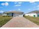 Front exterior of the house with a brick driveway, two car garage and manicured yard at 1203 Desmond St, Port Charlotte, FL 33952