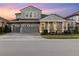 Inviting two-story home featuring a three-car garage, brick driveway, and a cozy front porch area with seating at 14215 Swiss Bridge Dr, Riverview, FL 33579