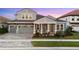 Charming two-story home with a well-manicured lawn, a brick driveway, and a covered front porch with chairs at 14215 Swiss Bridge Dr, Riverview, FL 33579
