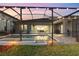 A beautiful screened pool with an attached seating area and string lights overhead at 14215 Swiss Bridge Dr, Riverview, FL 33579