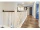 Bright hallway featuring wood floors, white railings, dark trim, and neutral wall color at 18304 Roseate Dr, Lutz, FL 33558