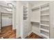 Custom walk-in closet features white shelves, drawers, and hanging areas with wood flooring at 3910 Gulf Blvd # 400, St Pete Beach, FL 33706