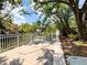 Landscaped backyard featuring wooden patio, green foliage, fence and water view providing a serene outdoor space at 7418 Bay Dr, Tampa, FL 33635