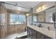 Modern bathroom with dual sinks, marble countertop, and a glass-enclosed shower at 7418 Bay Dr, Tampa, FL 33635
