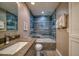 Modern bathroom featuring stylish blue tiled shower with a glass door and granite vanity at 8565 W Gulf Blvd # 17S, Treasure Island, FL 33706