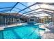 Gorgeous screened-in pool area with waterfall feature, outdoor kitchen, dining area and lounge chairs at 14214 Quintessa Ln, Lithia, FL 33547