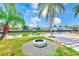 Beautiful backyard featuring a fire pit, lush lawn, palm trees, and waterfront views on a sunny day at 8722 Elmwood Ln, Tampa, FL 33615
