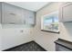 Bright laundry room with gray cabinets, a window and a geometric patterned floor at 8722 Elmwood Ln, Tampa, FL 33615