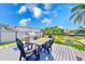 Waterfront outdoor dining area with a built-in grill, fire pit, and lush landscaping at 8722 Elmwood Ln, Tampa, FL 33615