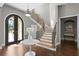Elegant foyer featuring hardwood floors, a staircase with wood and metal accents, and arched doorway at 1903 Haven Bend, Tampa, FL 33613