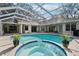 Outdoor pool and spa area, featuring a screen enclosure, potted plants, and nearby lounge area at 363 Sanctuary Dr, Crystal Beach, FL 34681