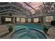 Enclosed patio featuring a swimming pool with attached spa surrounded by lush potted plants at 363 Sanctuary Dr, Crystal Beach, FL 34681