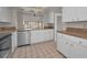 Bright kitchen featuring white cabinets, stainless steel appliances, and a view to the living area at 8005 Bardmoor Pl # 202I, Seminole, FL 33777