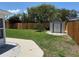 Fenced backyard with grassy lawn, storage shed, and concrete walkway at 8418 Flagstone Dr, Tampa, FL 33615