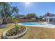 Backyard with a beautiful pool, palm trees, and colorful flower bed at 8418 Flagstone Dr, Tampa, FL 33615