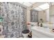 Clean bathroom features a patterned shower curtain, white fixtures, and a well-lit mirror at 16211 Rambling Vine W Dr, Tampa, FL 33624