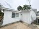 Exterior view of a home with a white door, window and white painted stucco exterior at 4925 Beacon Hill Dr, New Port Richey, FL 34652