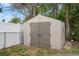 Durable outdoor storage shed featuring a double-door design in a fenced yard at 4925 Beacon Hill Dr, New Port Richey, FL 34652