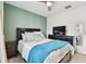 Cozy bedroom with a wall-mounted TV, dresser, and comfortable bedding, illuminated by a ceiling fan at 6684 Devlin Ln, Wesley Chapel, FL 33545